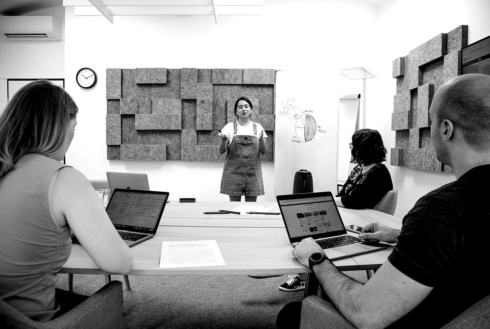 Reunión de trabajo con varias personas y portátiles alrededor de una mesa.