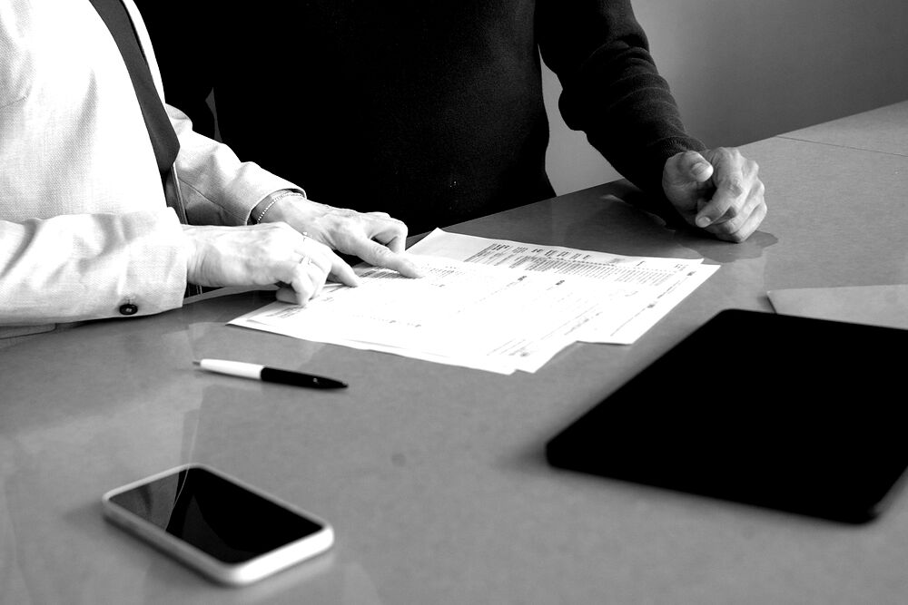 Dos personas revisando documentación sobre una mesa de trabajo.